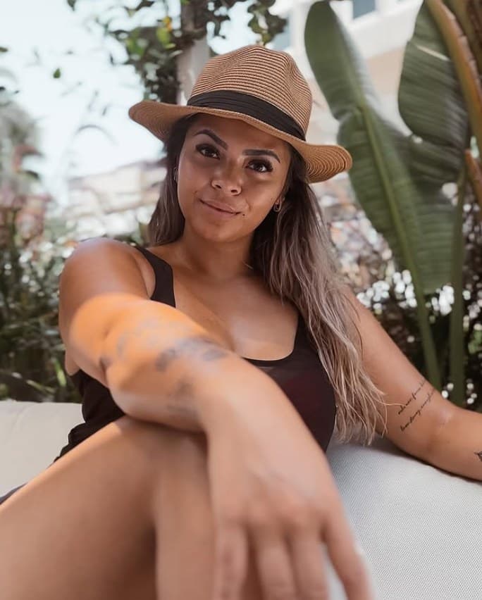 Michelle in a straw hat on a resort lounger between tropical plants